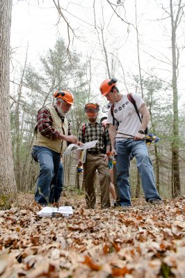 students and instructor working in forest with a map